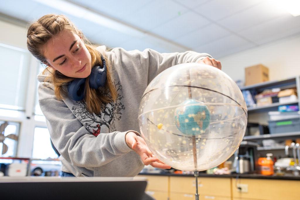 Putney student looking at a globe during a science class